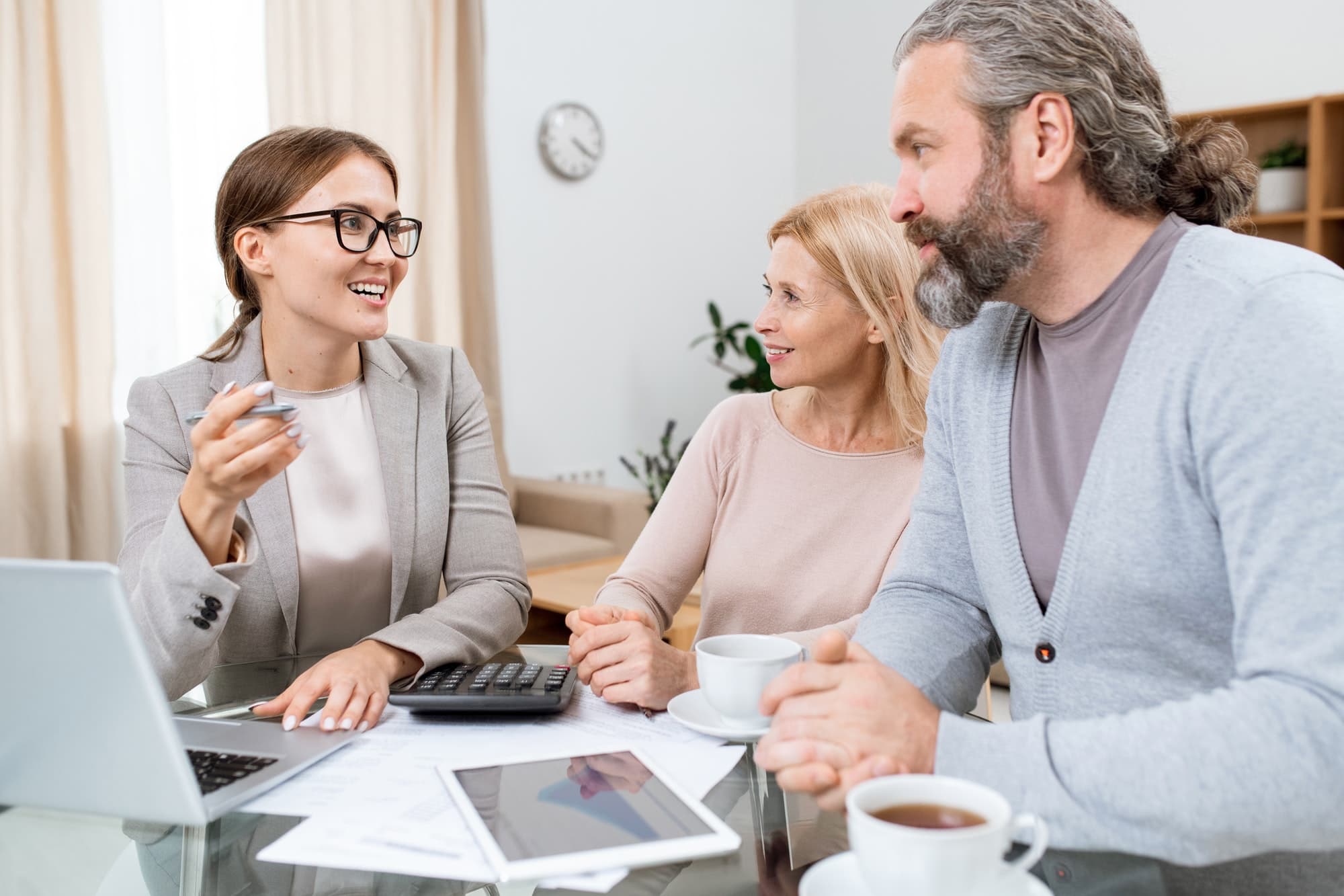 Young cheerful financial advisor or agent consulting mature husband and wife